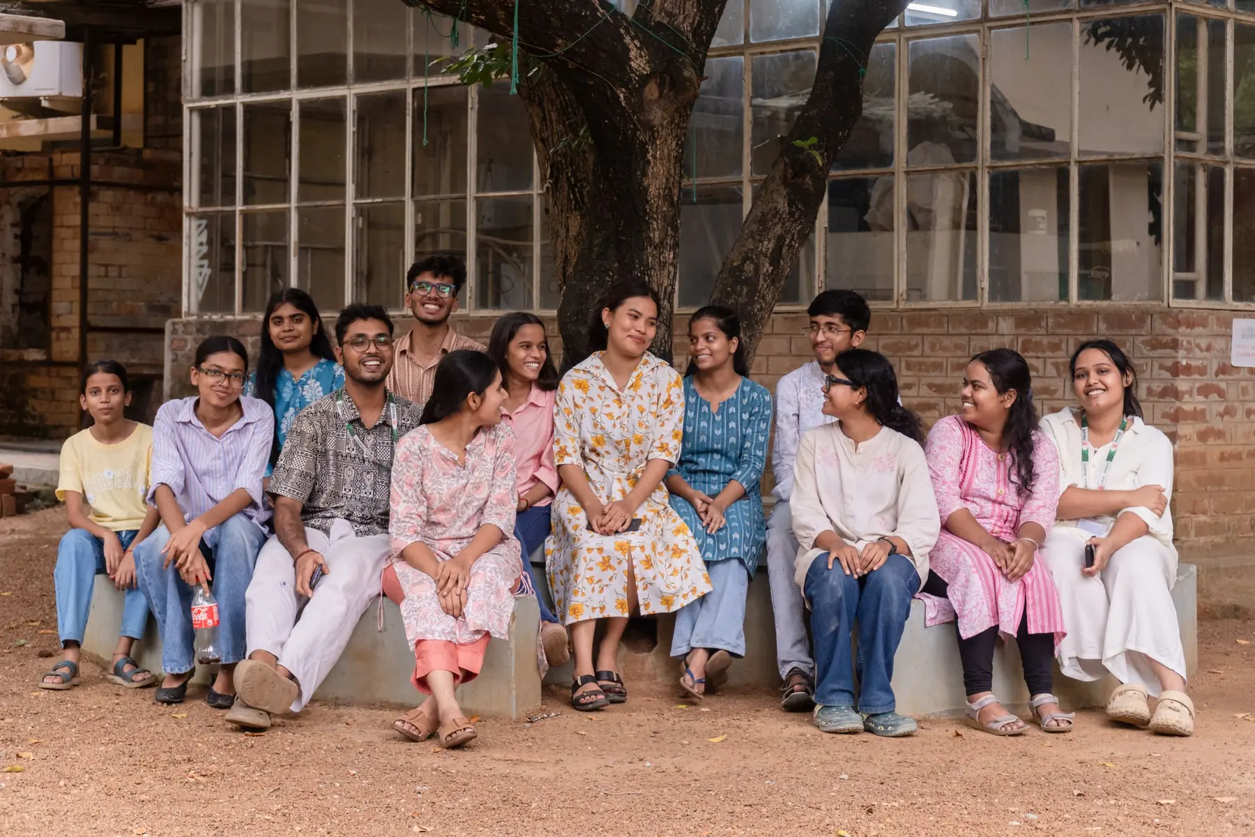 A group of college students sitting together under a tree on campus