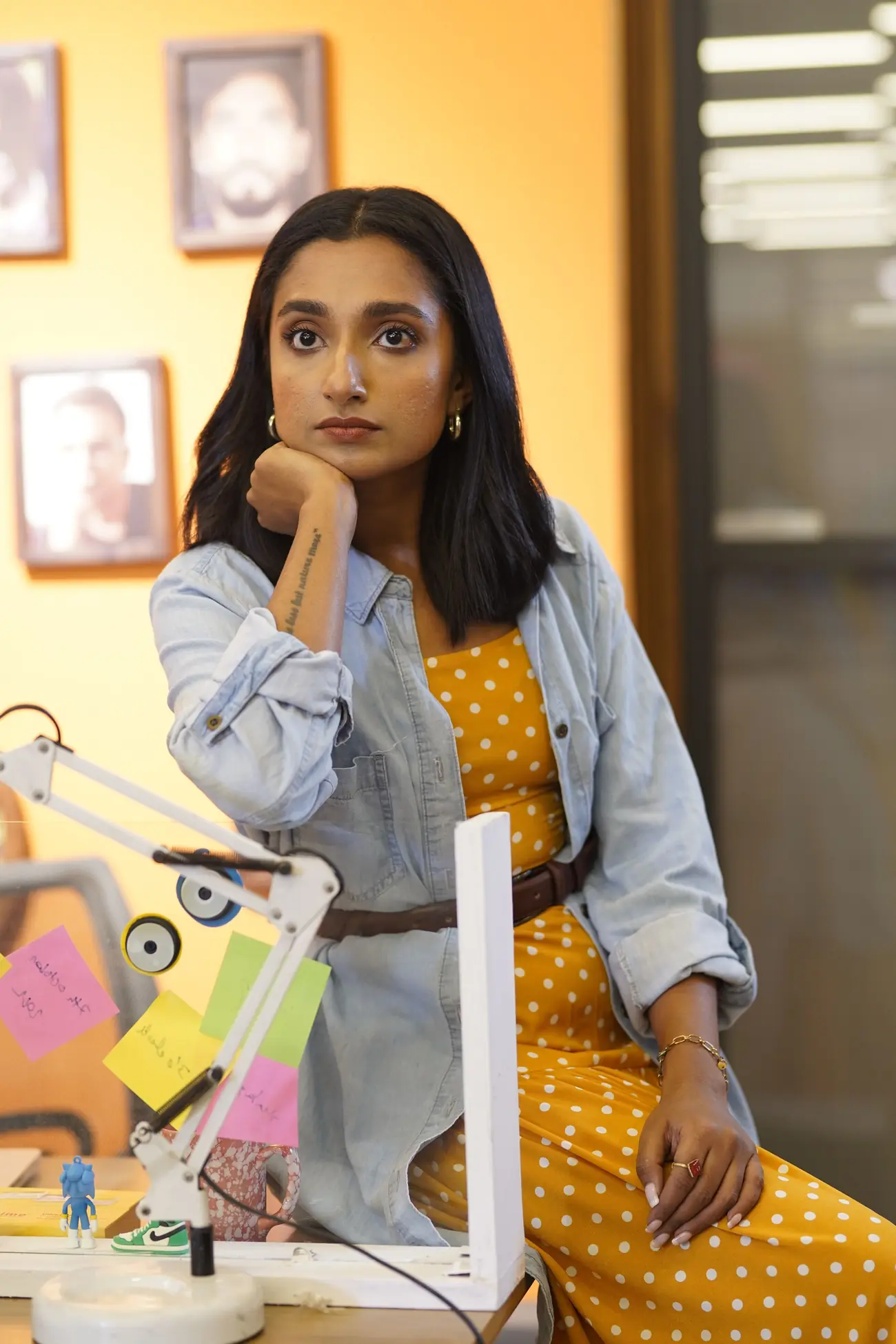 A young professional woman thinking at her desk in a bright office